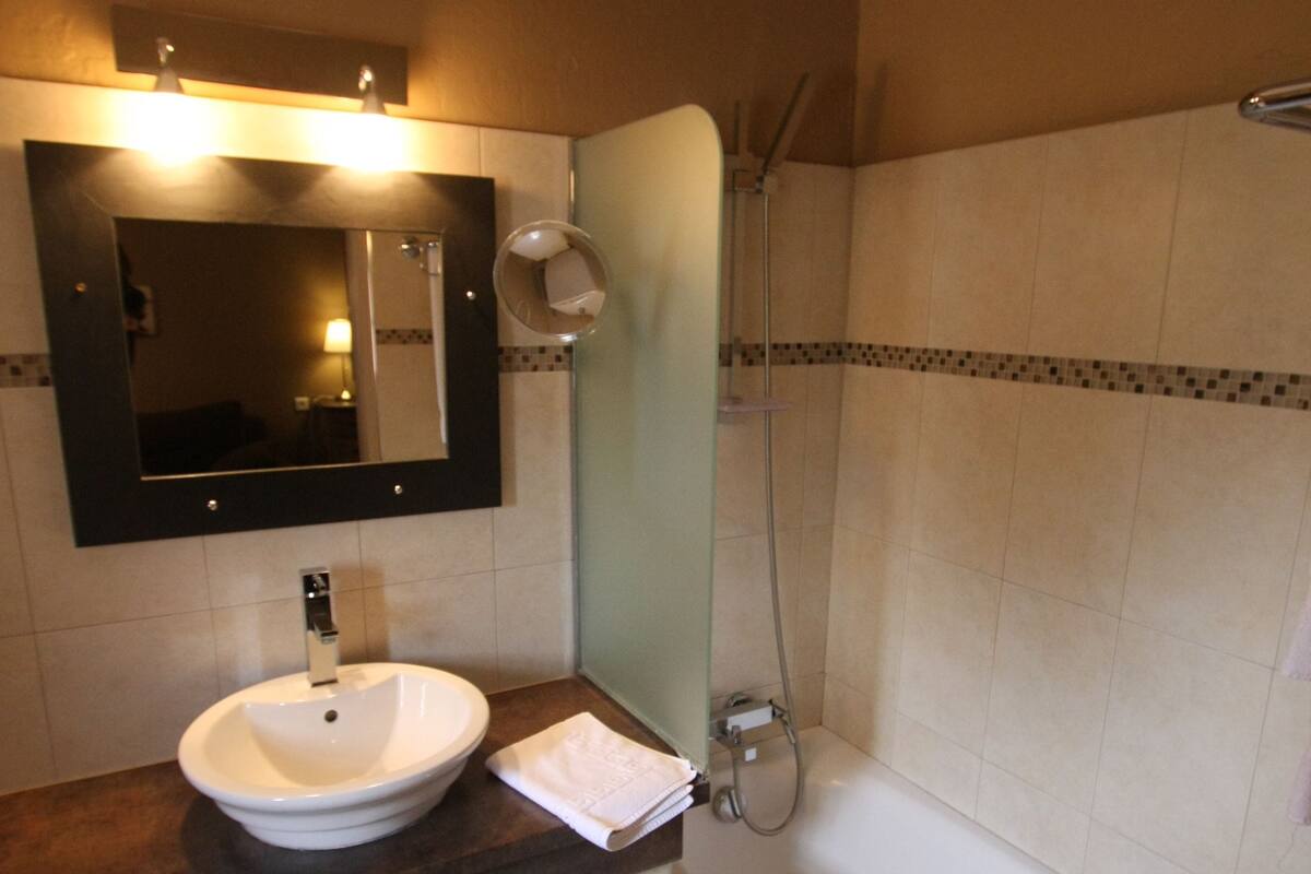 A bathroom with a white sink, a mirror, a shower, and a towel rack.