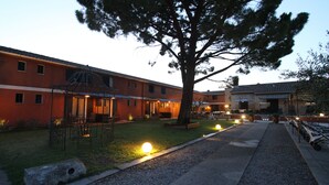 A building with a covered outdoor seating area, a paved walkway, and a parking lot with cars. - Hotel Van Gogh (St.-Rémy-de-Provence)