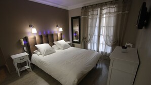 A hotel room with a large bed, bedside lamps, a nightstand, a dresser, and a mirror.
