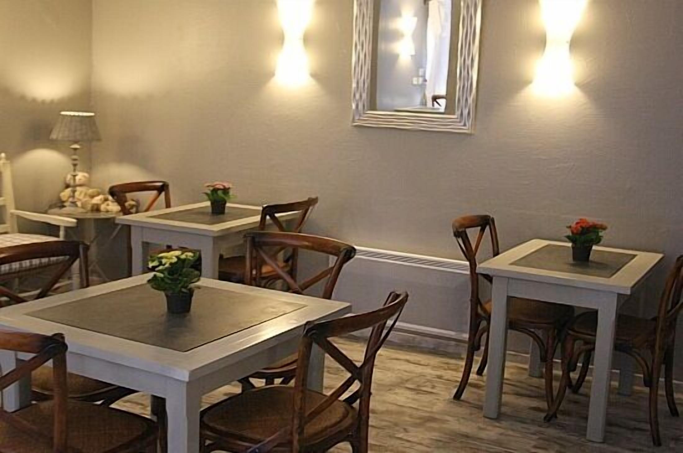 A dining area with multiple tables and chairs, each with a small plant on the table.