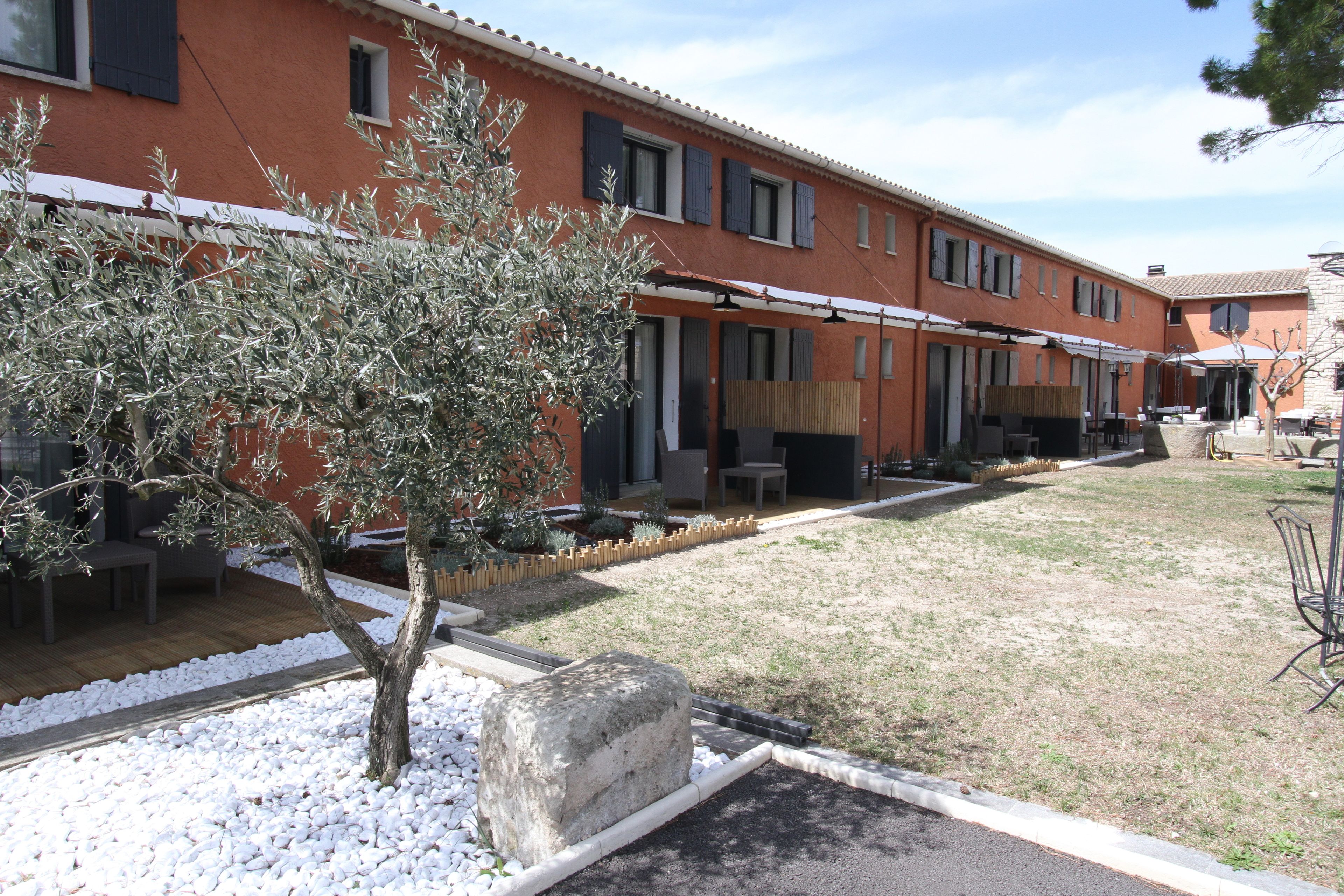 A courtyard with outdoor seating, a tree, and a building with multiple windows and doors.