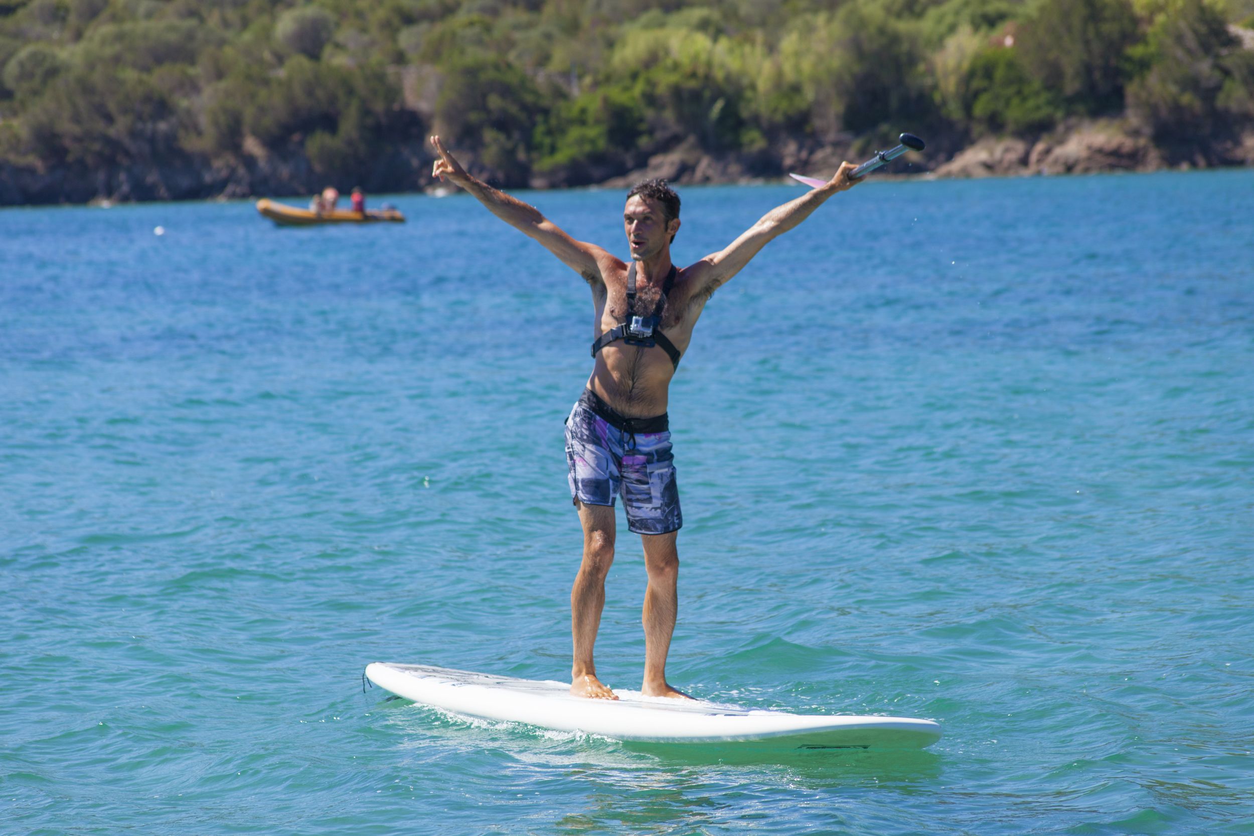 Eine Person steht auf einem Surfbrett im Wasser, die Arme nach außen gestreckt.