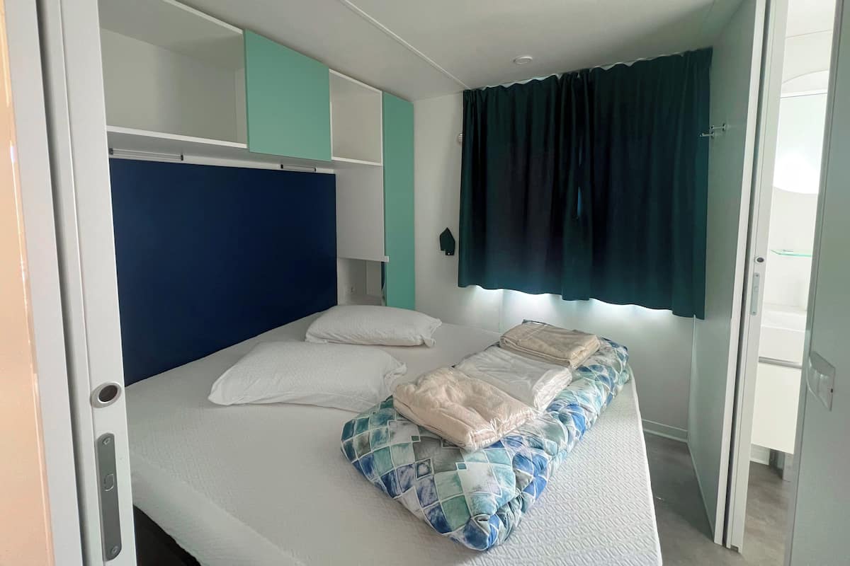 Un lit simple avec une tête de lit bleue, des oreillers blancs et une couvre-lit matelassée.