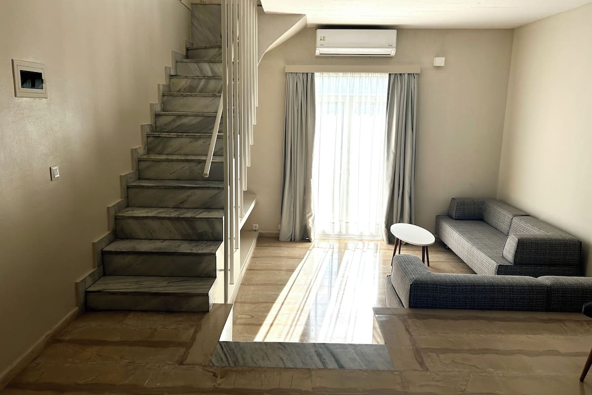 A spacious living area with a marble staircase, a sofa, and a small table.