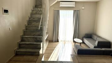 A spacious living area with a marble staircase, a sofa, and a small table.