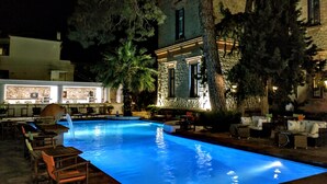 Una piscina con un edificio de piedra y zona de estar al aire libre.