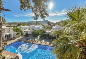 Una piscina al aire libre, sombrillas, sillones reclinables de piscina