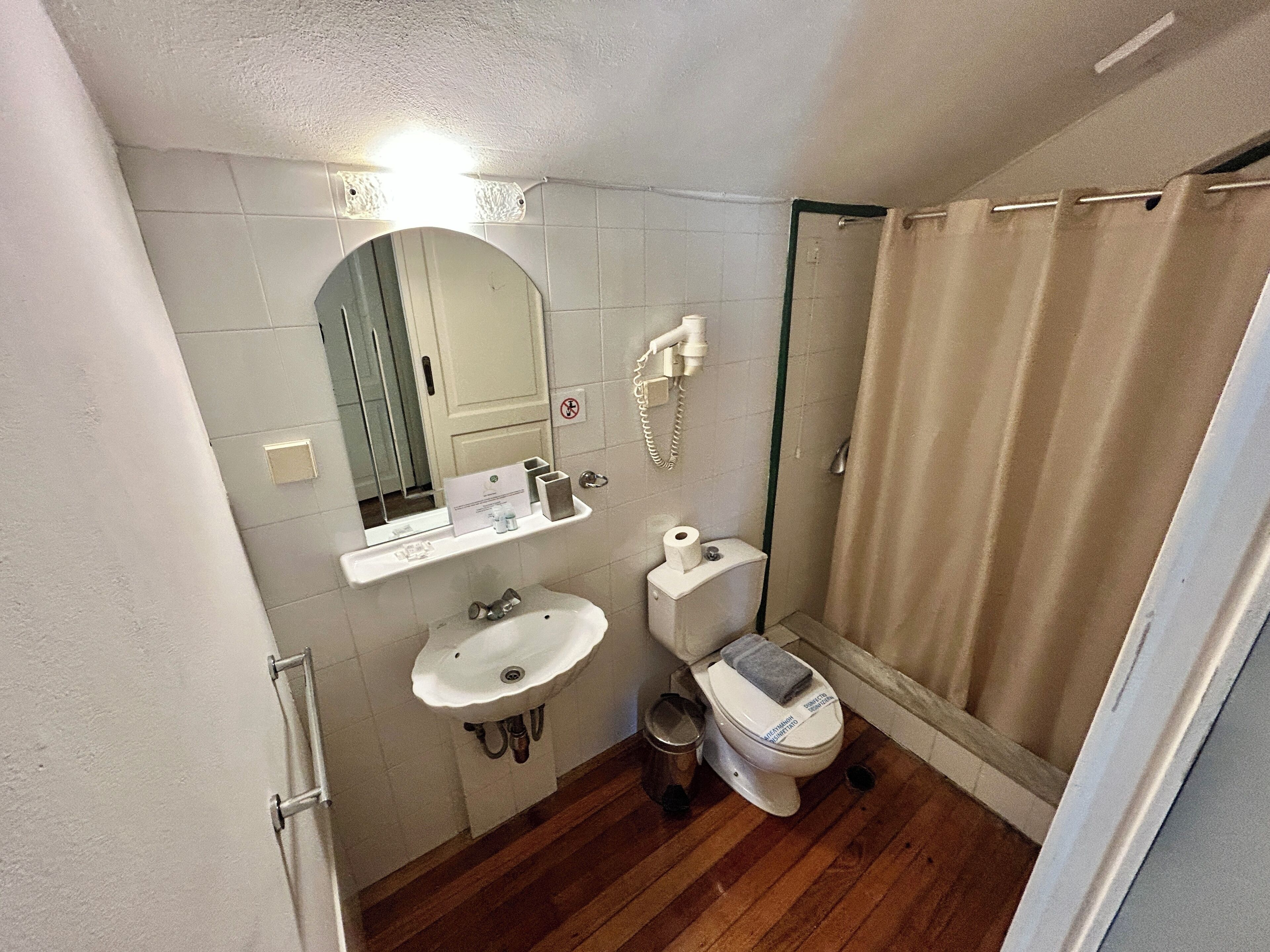A compact bathroom with a sink, toilet, and shower.