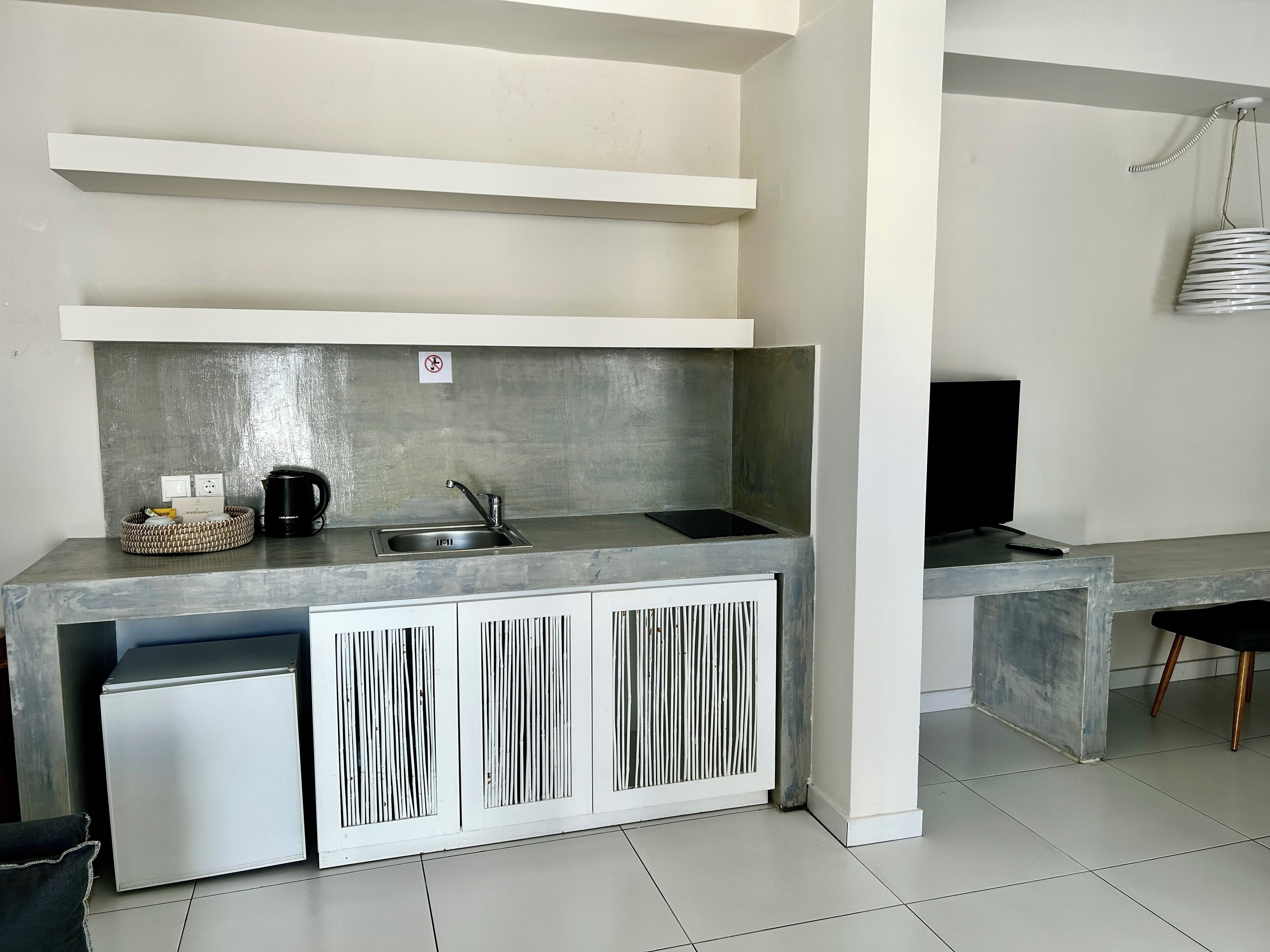 A compact kitchenette with a built-in sink, a small refrigerator, and a microwave.