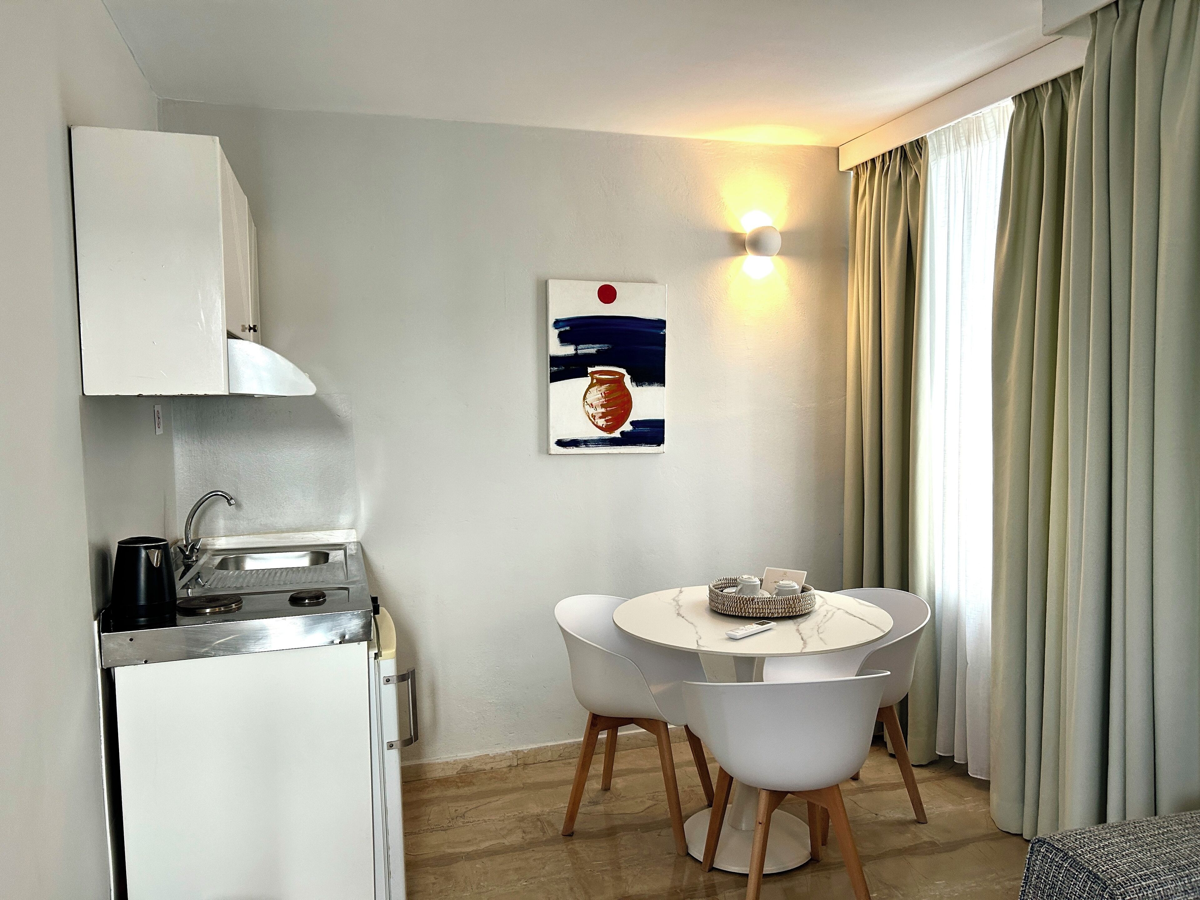 A compact kitchen with a refrigerator, sink, and a small dining area with a table and chairs.