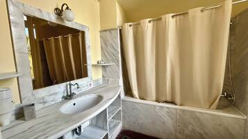 A bathroom with a marble sink, a mirror, a shower, and a towel rack.