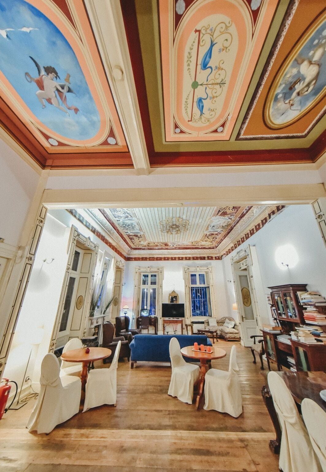 A spacious room with a high ceiling, ornate ceiling decorations, a blue sofa, and a wooden coffee table.