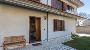 A house with a tiled patio, a wooden bench, and a door leading to a room. - ANAELEHOUSEAPARTMENTS L.T.B. (Arborea)