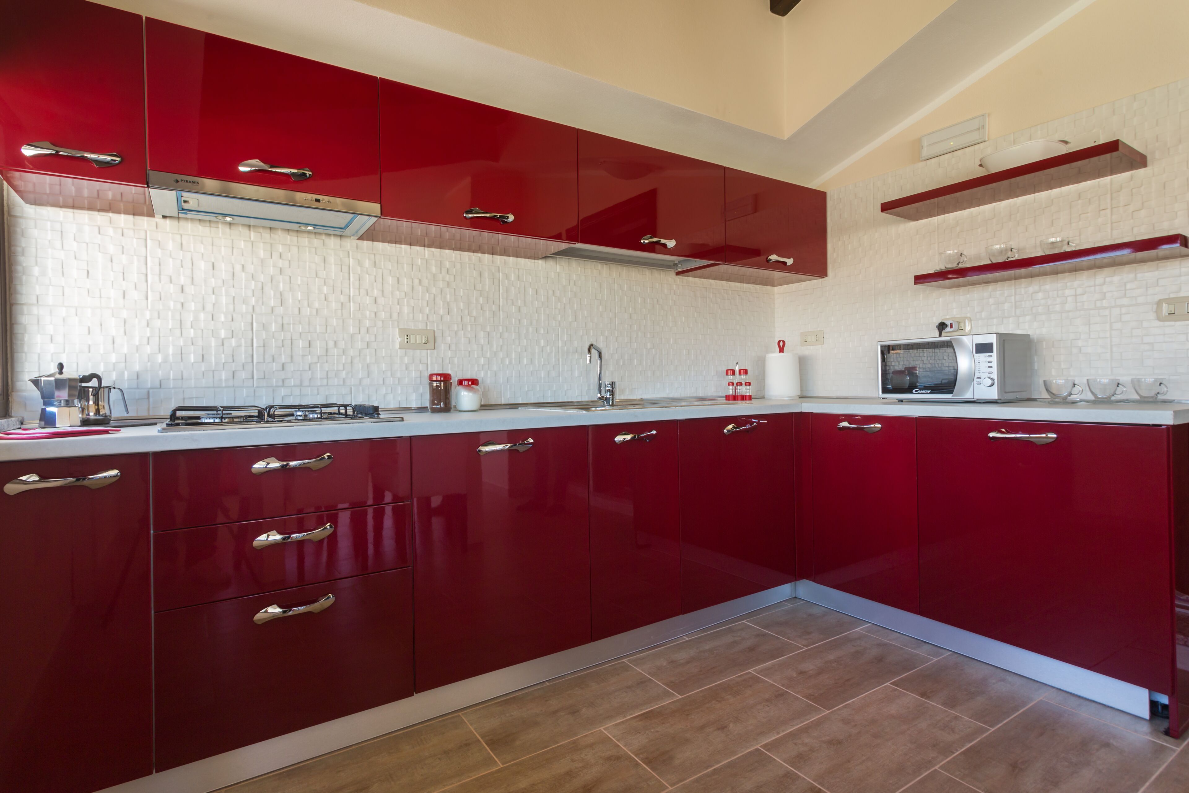Una cocina moderna con armarios rojos, un microondas y un salpicadero de azulejos.