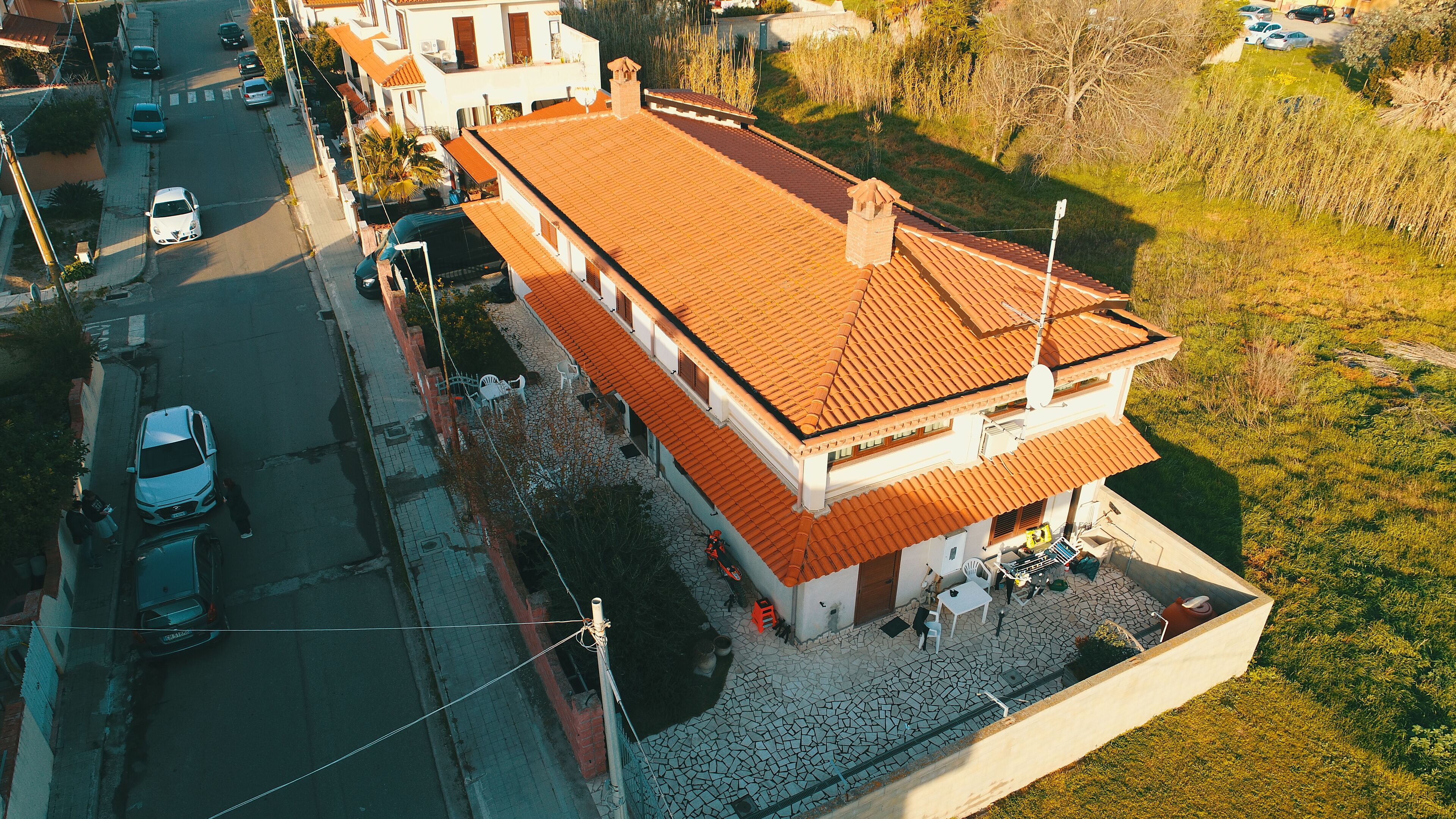 An aerial view of a two-story building with a tiled roof, a paved driveway, and a small garden area.