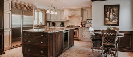 A modern kitchen with a large island, stainless steel appliances, and a dining area with a table and chairs.