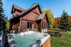 A wooden cabin with a hot tub, picnic table, and outdoor seating area. - Chalets Royal Laurentien (Mont-Blanc)