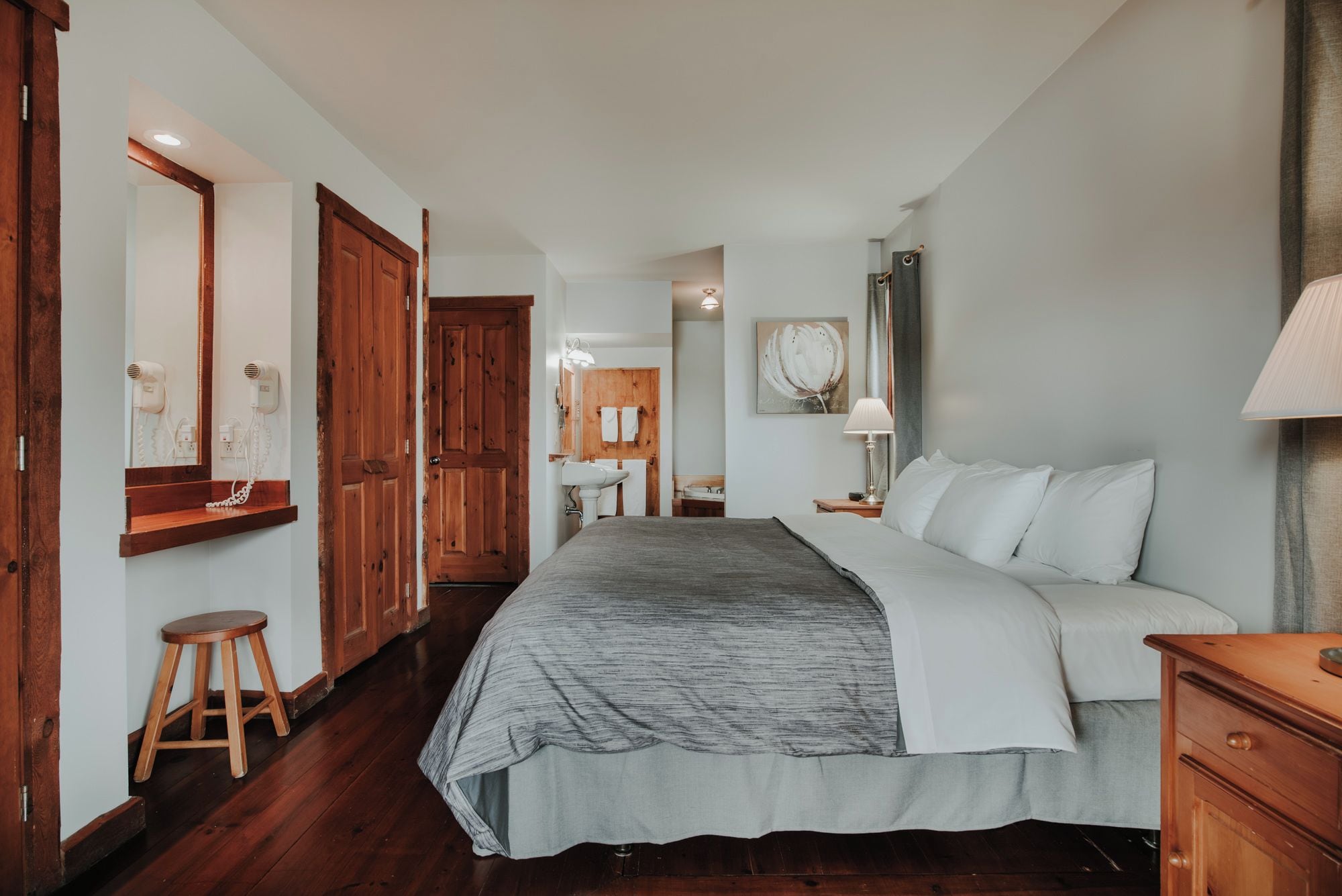 Een slaapkamer met een groot bed, een houten garderobe en een badkamer die door een open deur zichtbaar is.