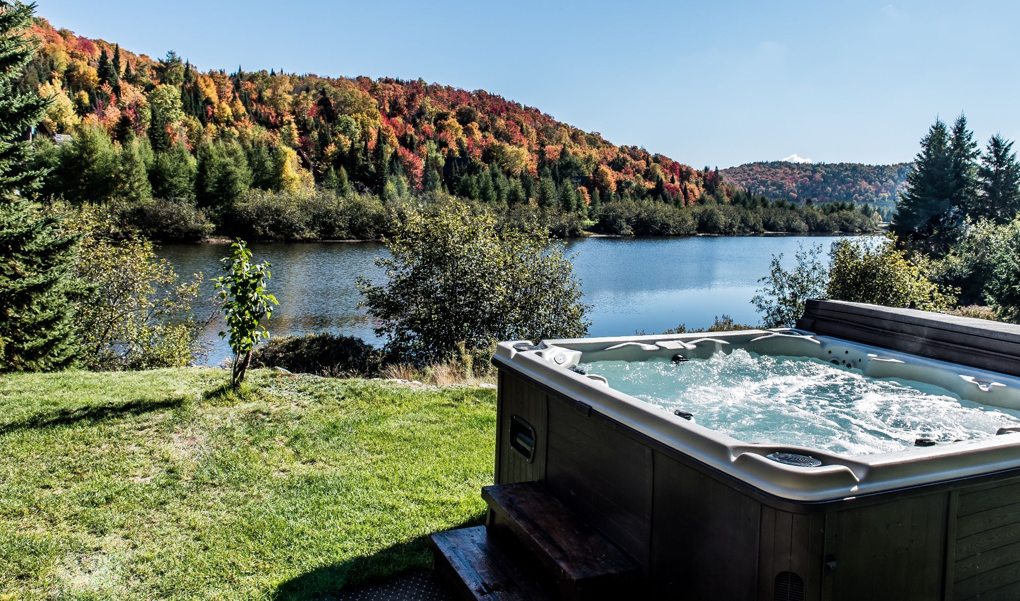 A hot tub with a view of a lake and autumn foliage.