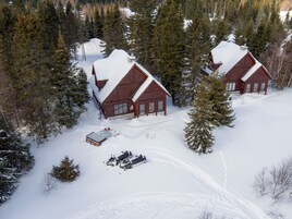 Dos cabañas de madera rodeadas por un bosque cubierto de nieve.