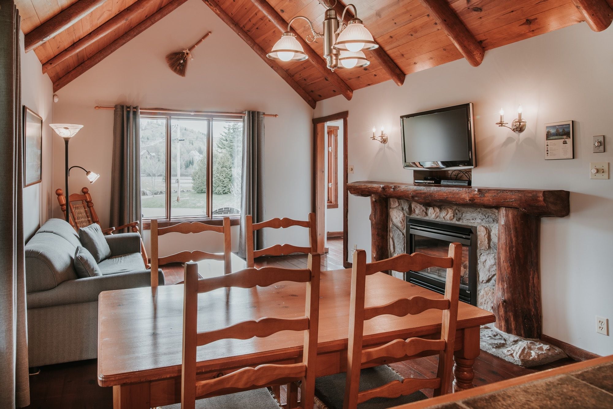 A cozy living room with a fireplace, wooden dining table, and chairs.
