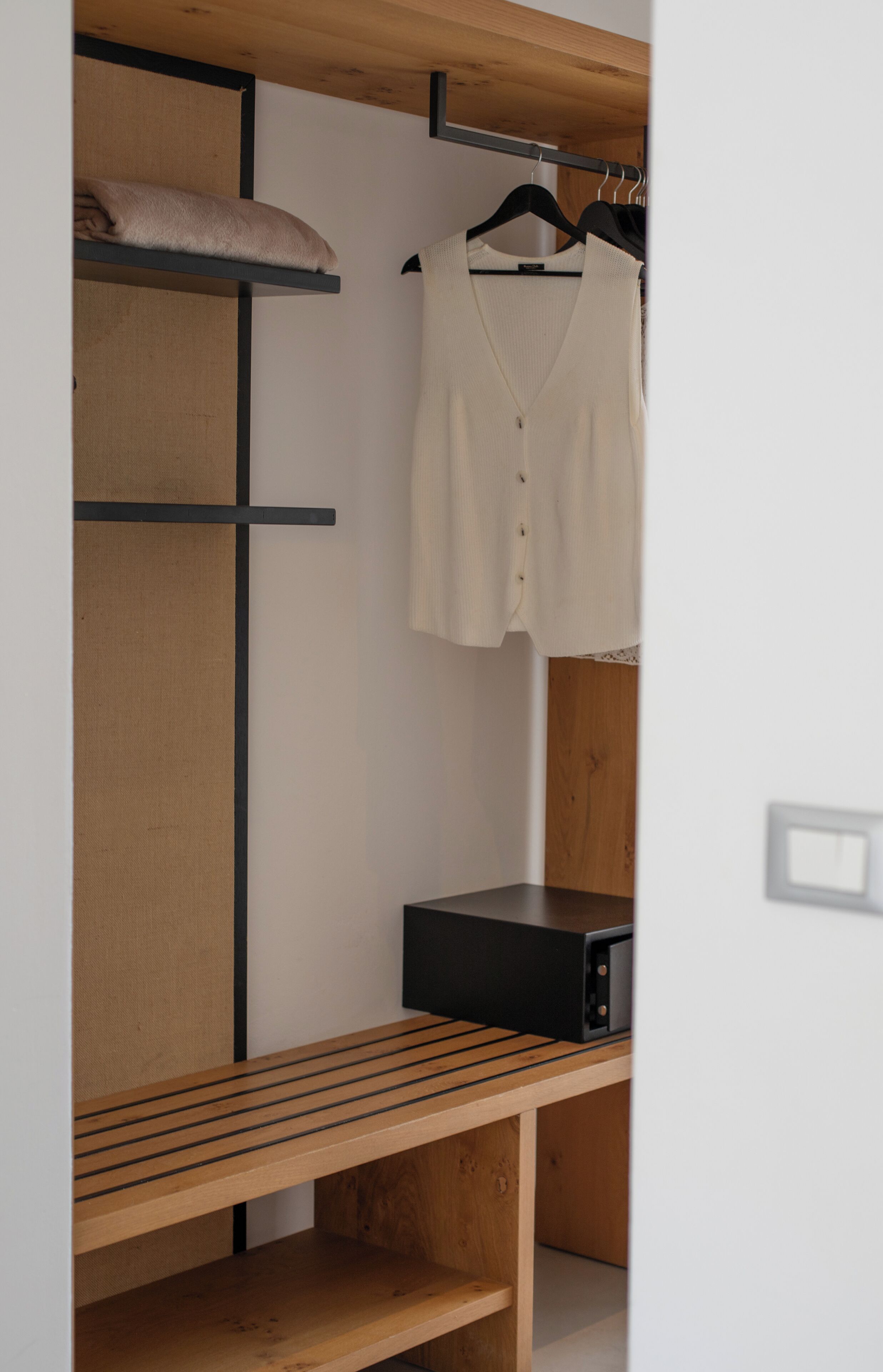 Une petite pièce comprenant un lit superposé, un banc en bois, une radio noire et un vêtement suspendu.