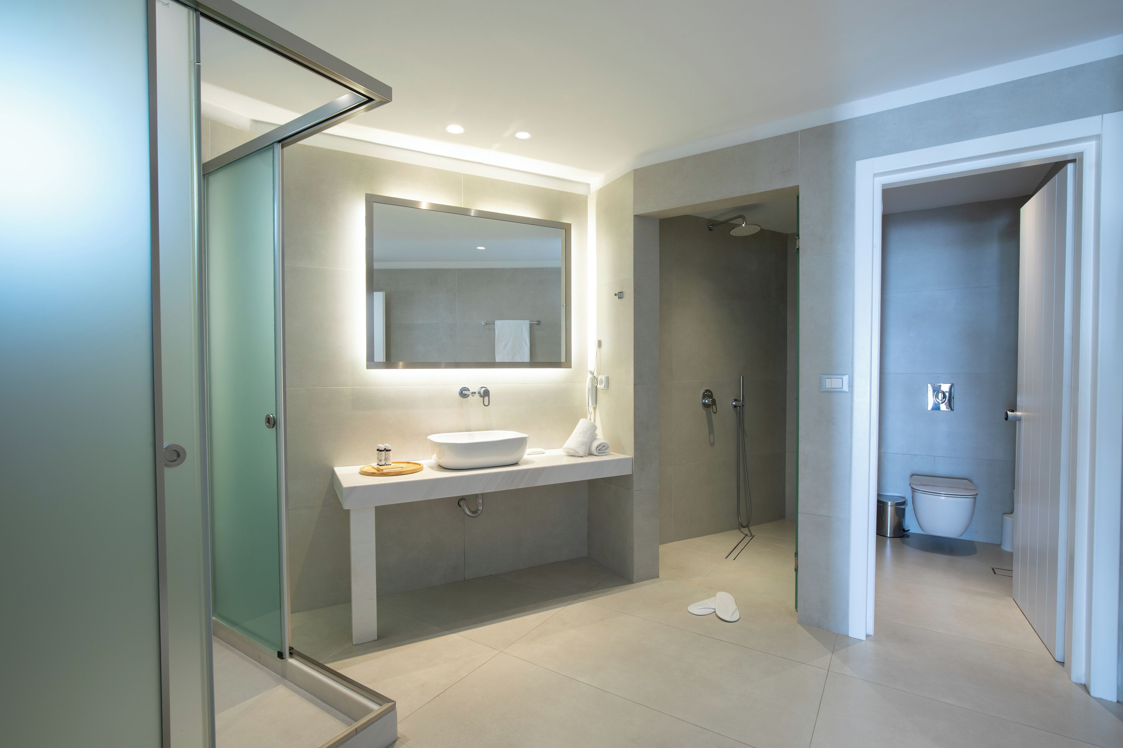 A modern bathroom with a glass shower enclosure, a large mirror, and a white sink.