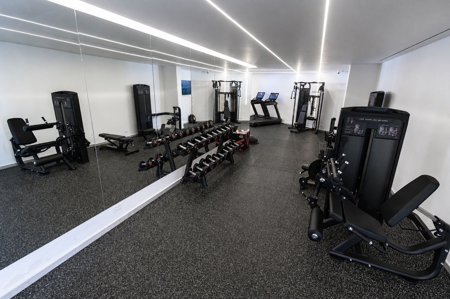 A gym with various exercise equipment, including dumbbells, benches, and weight machines.