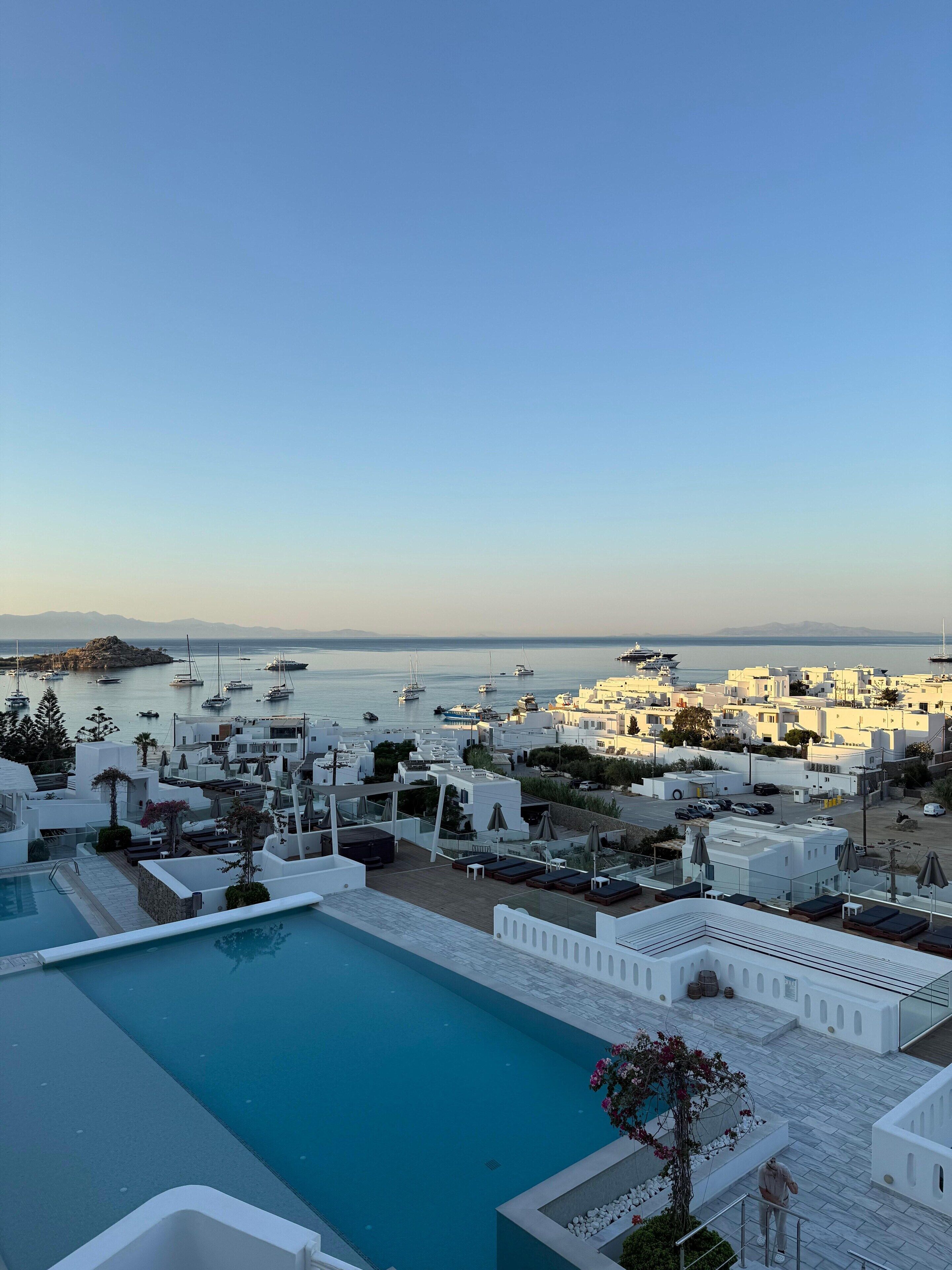 A rooftop pool with a view of a coastal town and the sea.