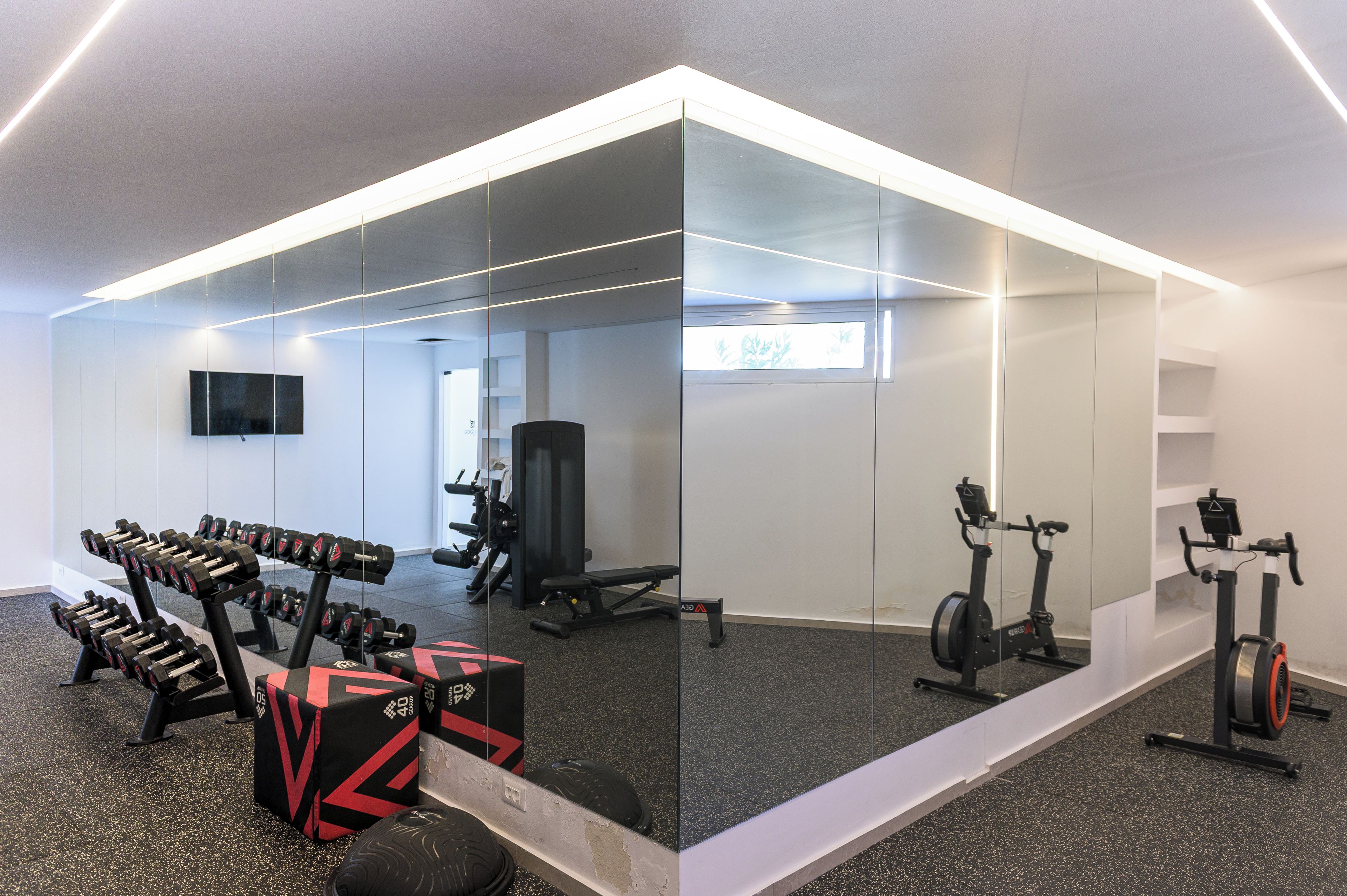 Un gimnasio con equipo de ejercicio, un televisor y un espejo.