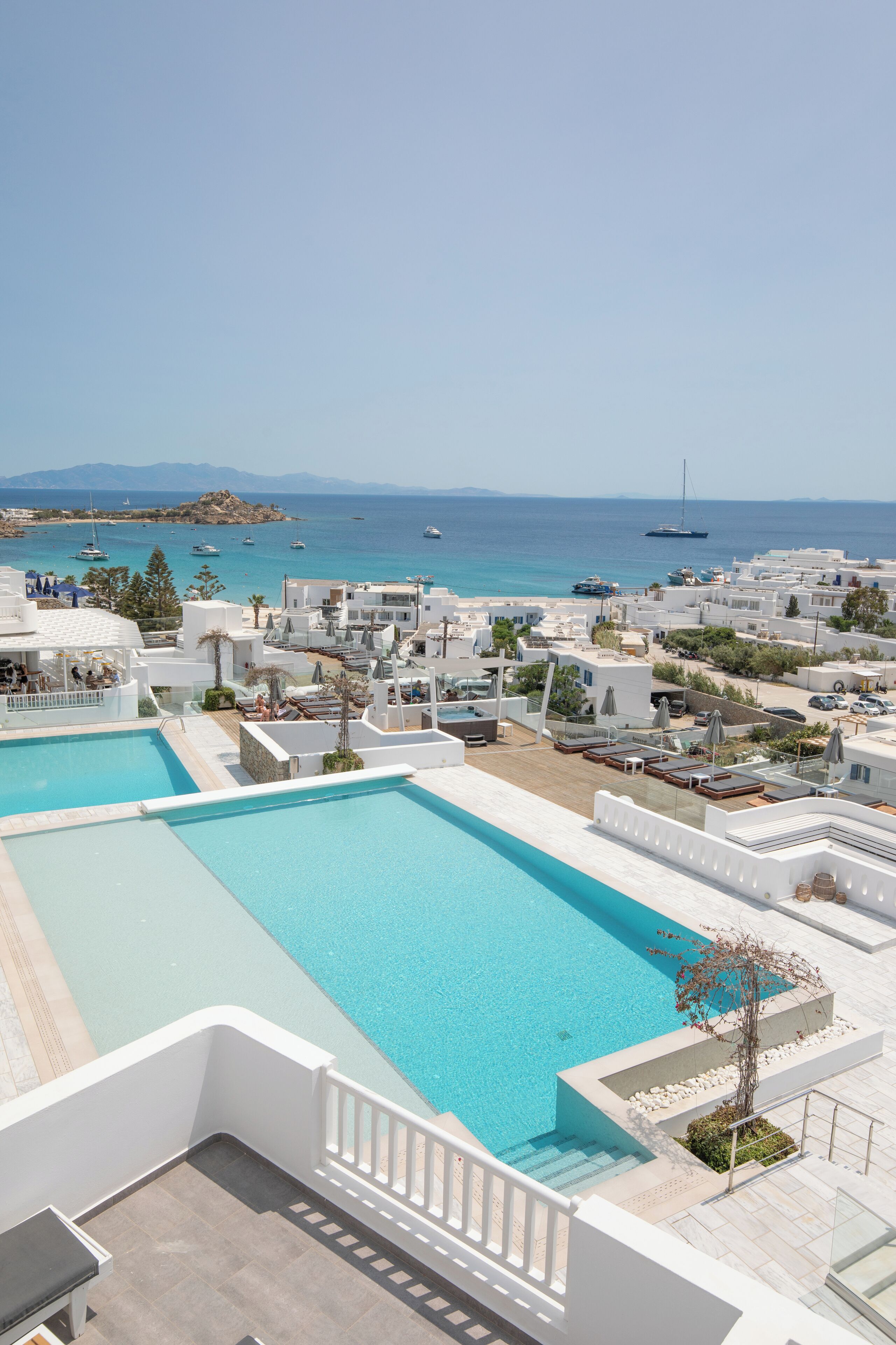 A resort with a large pool, white buildings, and a view of the sea.