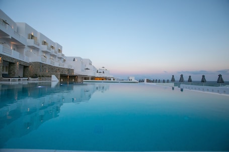A poolside view of a resort with a clear sky, a pool, and a building with balconies.