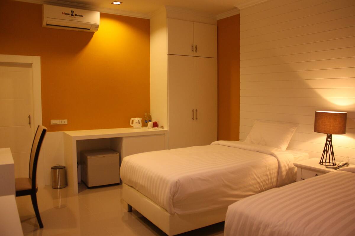 A hotel room with two beds, a desk, and a chair.