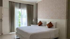 Een hotelkamer met een groot bed, een nachtkastje, een lamp en uitzicht op groen.