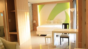 Een moderne hotelkamer met een groot bed, een eettafel en een groene accentmuur.
