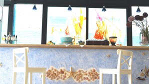 A bar area with a blue textured wall, two white bar stools, and a window with a view of the sea. - Hotel Lux (Cesenatico)