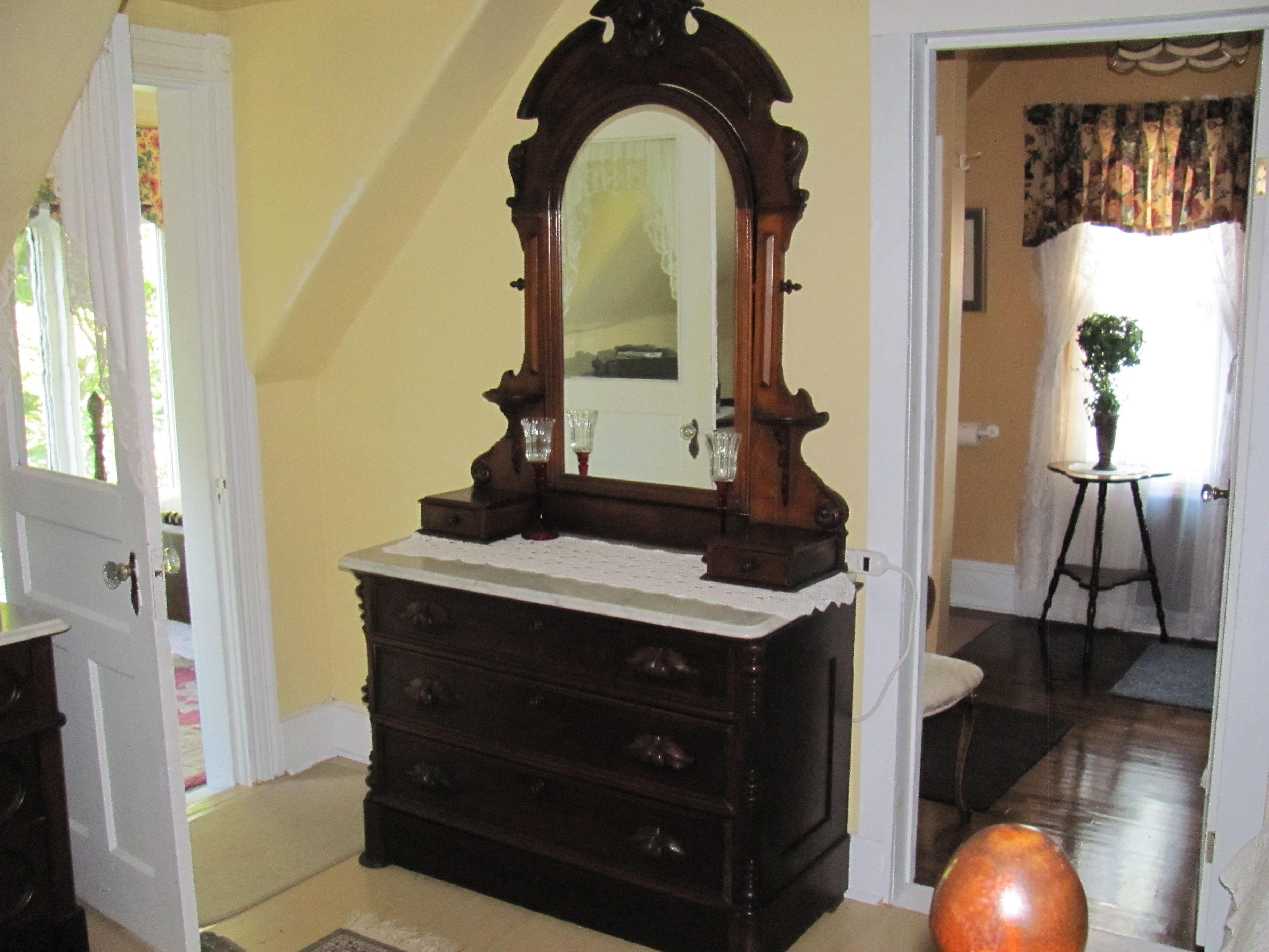 A room with a wooden dresser, a mirror, and a potted plant.