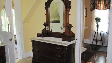A room with a wooden dresser, a mirror, and a potted plant.