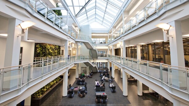 A multi-level atrium with glass railings, a central staircase, and seating areas. - Saint Mary's University Residence Summer Accommodations (Halifax)