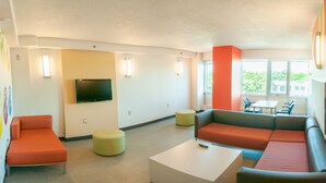 A modern living room with a flat-screen TV, a sofa, a coffee table, and a small table with chairs. - Saint Mary's University Residence Summer Accommodations (Halifax)