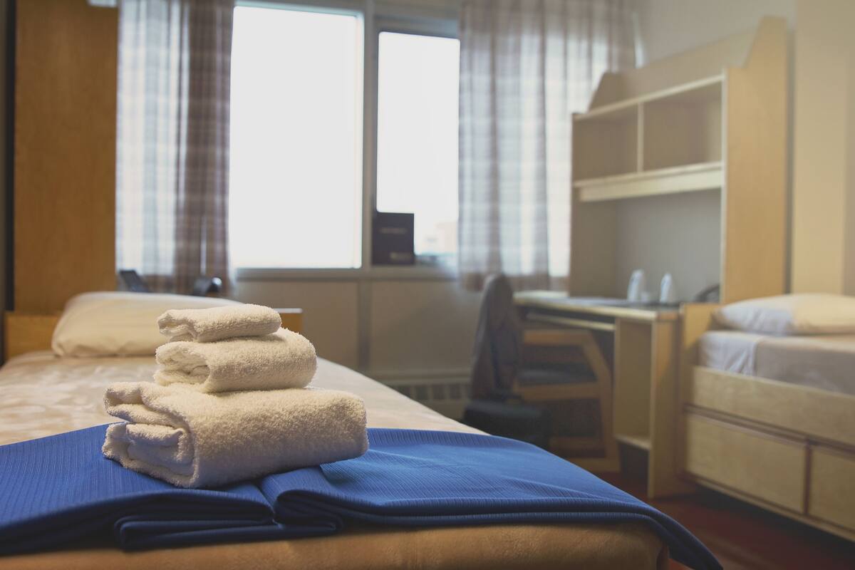 Una habitación de hotel con una cama, un escritorio y una litera.