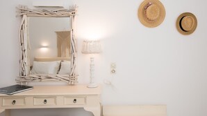 Une chambre à coucher avec un lit, une table de chevet, une lampe, un miroir et deux chapeaux accrochés au mur.