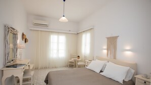 Une chambre d’hôtel comprenant un lit, des tables de chevet, un bureau avec une chaise, un miroir et un luminaire suspendu.