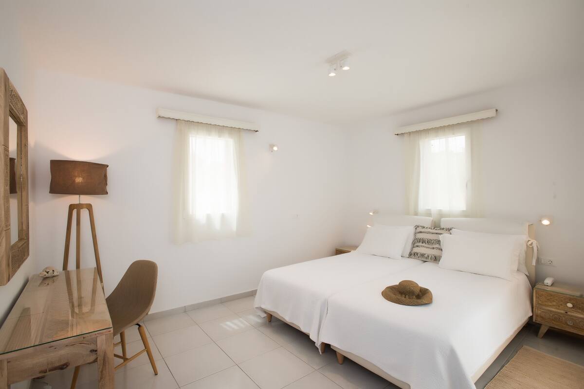 A bedroom with a bed, a desk, a chair, and a lamp.
