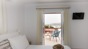Une chambre d’hôtel avec un lit, un téléviseur à écran plat, un balcon avec une table et des chaises, et une vue sur la mer.
