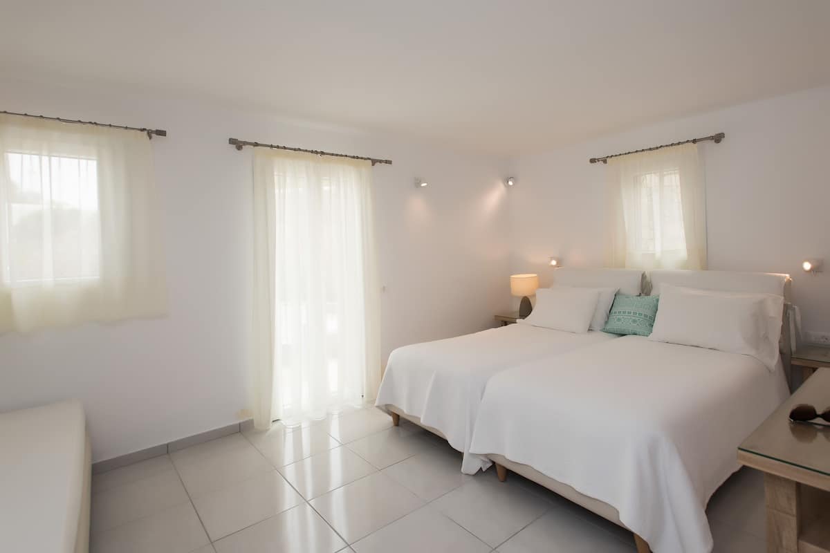 A hotel room with a large bed, two bedside tables, a chair, and a window with curtains.