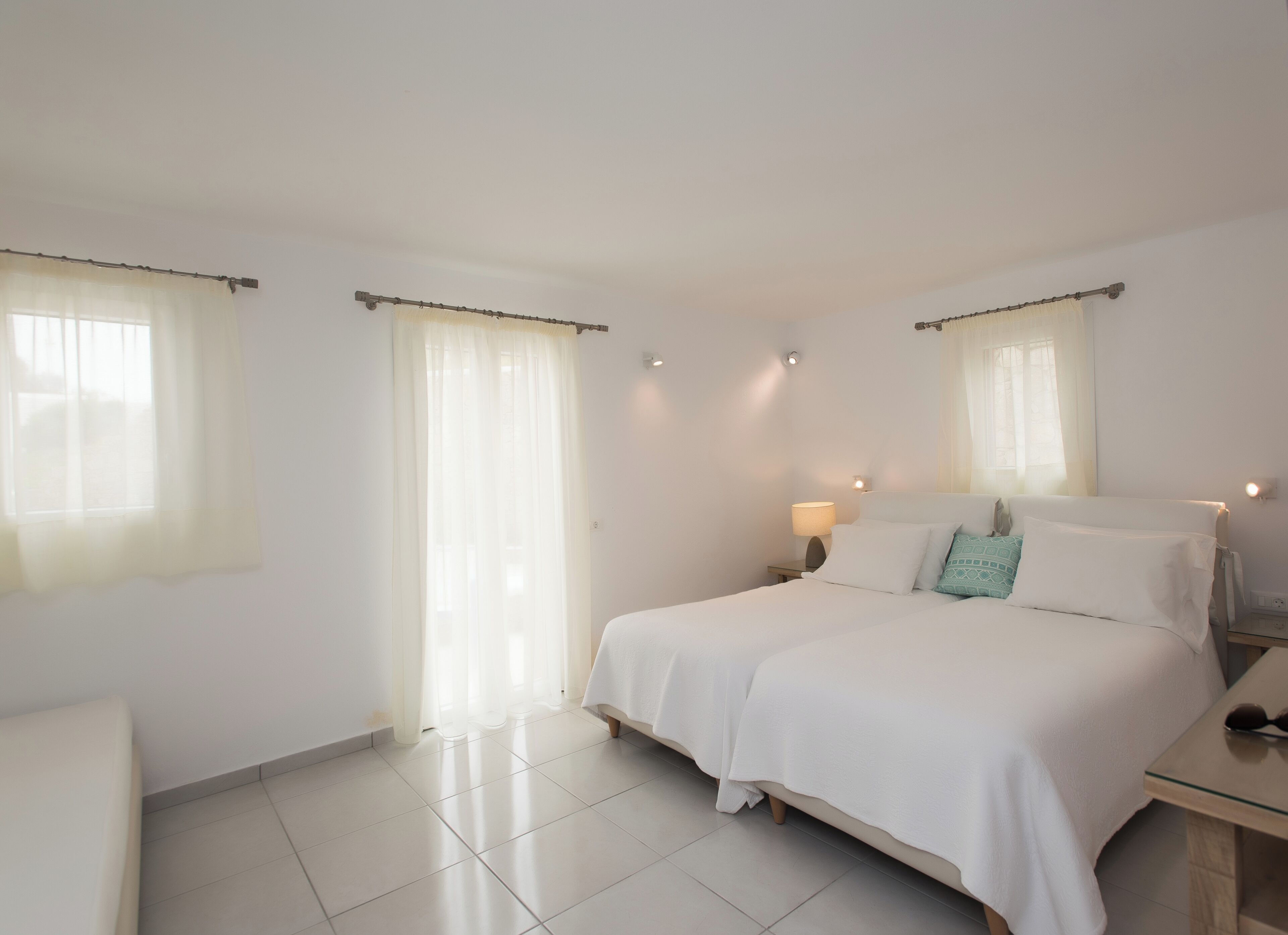 A hotel room with a large bed, two bedside tables, a chair, and a window with curtains.