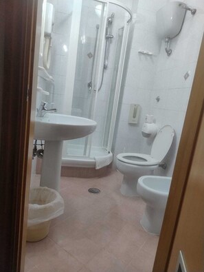A bathroom with a sink, toilet, bidet, and shower.