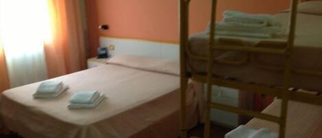 Una cama individual con estructura y cabecero de madera, una mesita de noche con lámpara y una ventana con cortinas.