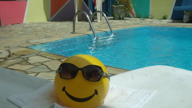 Un objecte groc amb ulleres de sol i una cara somriure sobre una tovallola blanca a la piscina.